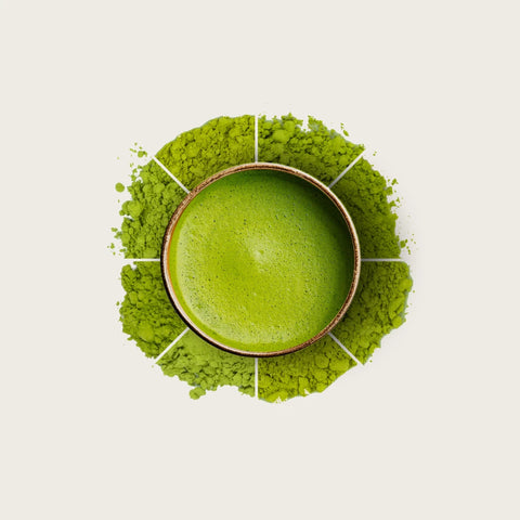 A top-down view of a small bowl filled with bright green powder, surrounded by a circular ring of finely ground green powder on a light beige background.