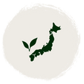 A dark green silhouette map of Japan with two leaves, centered inside a large textured off-white circle on a white background.